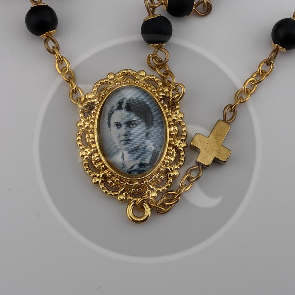A gold-framed centrepiece of a catholic Rosary with a small black and white photograph of St. Edith Stein.
